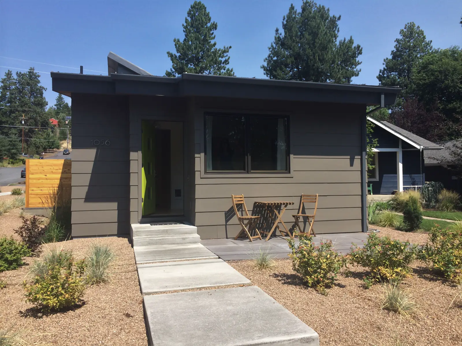 A small detached accessory dwelling with light wood siding and a dark gable roof beside a gravel path in Oregon.